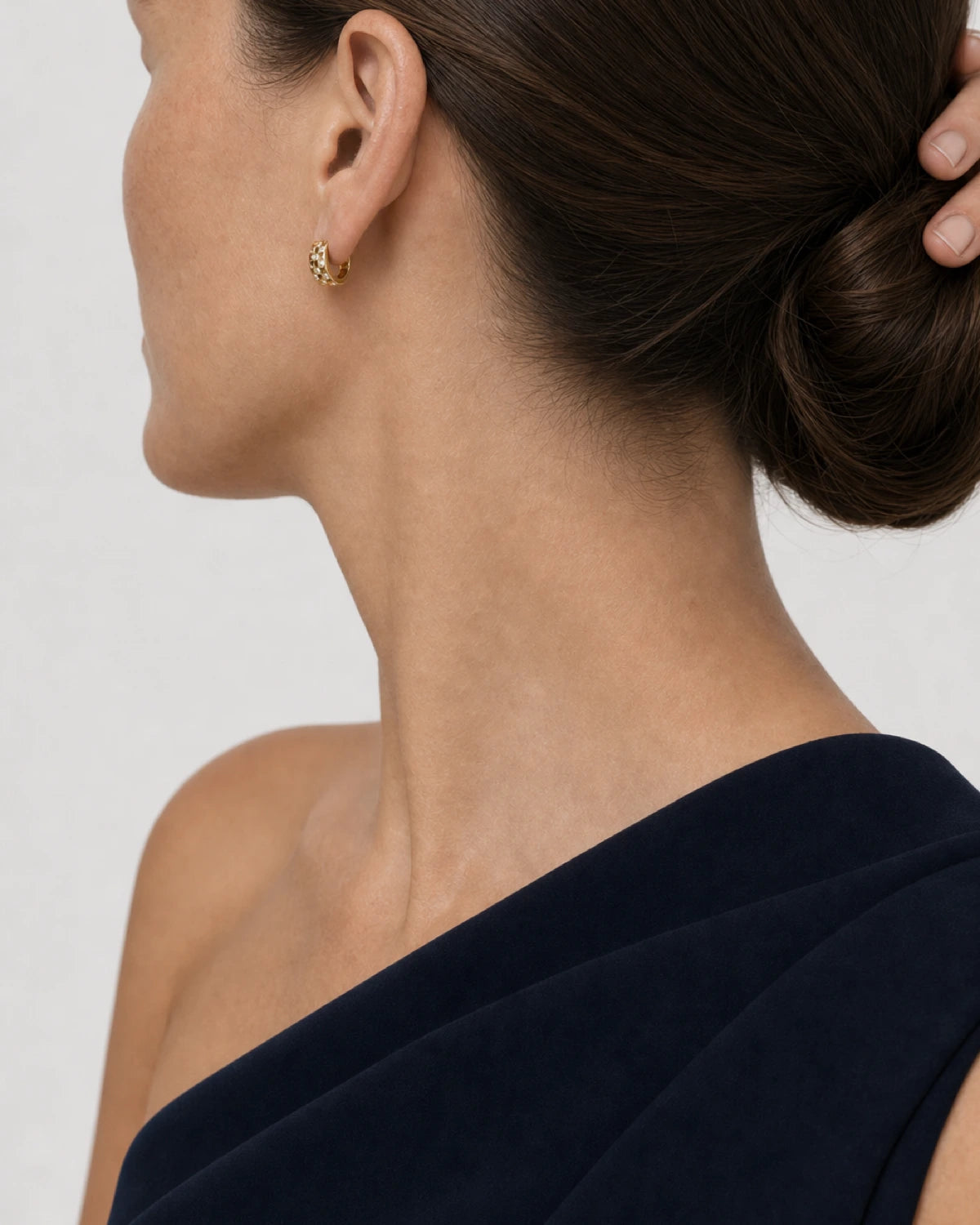 Eye-free rear portrait of Cecily wearing the compact gold Lisette huggie