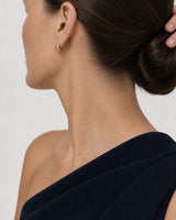 Eye-free rear portrait of Cecily wearing the compact gold Lisette huggie