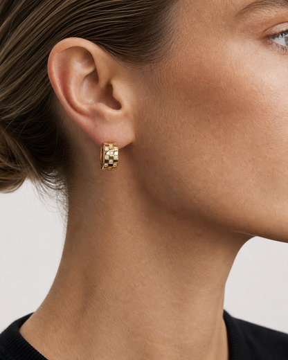 Close ear view of one Lisette gold checkerboard huggie