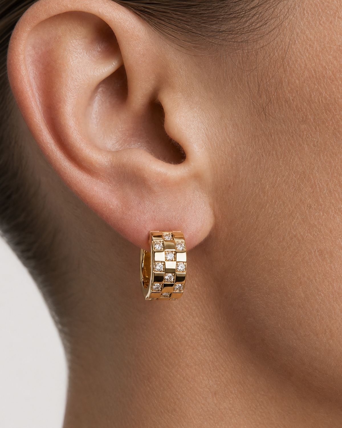 Extreme ear macro of Lisette gold checkerboard crystal huggie