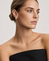 Model in a black linen Mallorca dress wearing Lisette gold checkerboard huggies