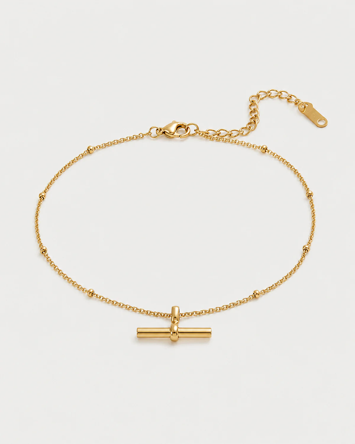 Lucille gold beaded T-bar bracelet on a pale dove-grey background