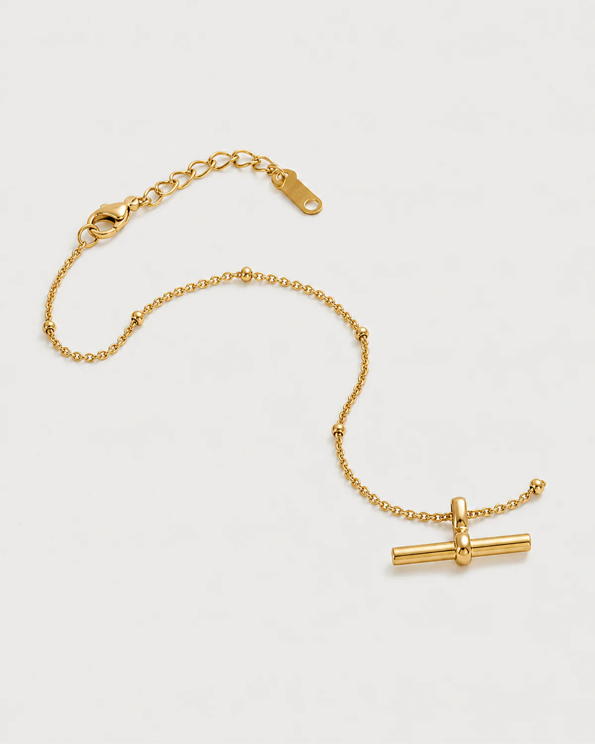 Lucille gold-tone T-bar bracelet in an alternate arrangement on pale grey