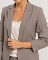 Human-scale styling detail of the Lucille bracelet with taupe tailoring