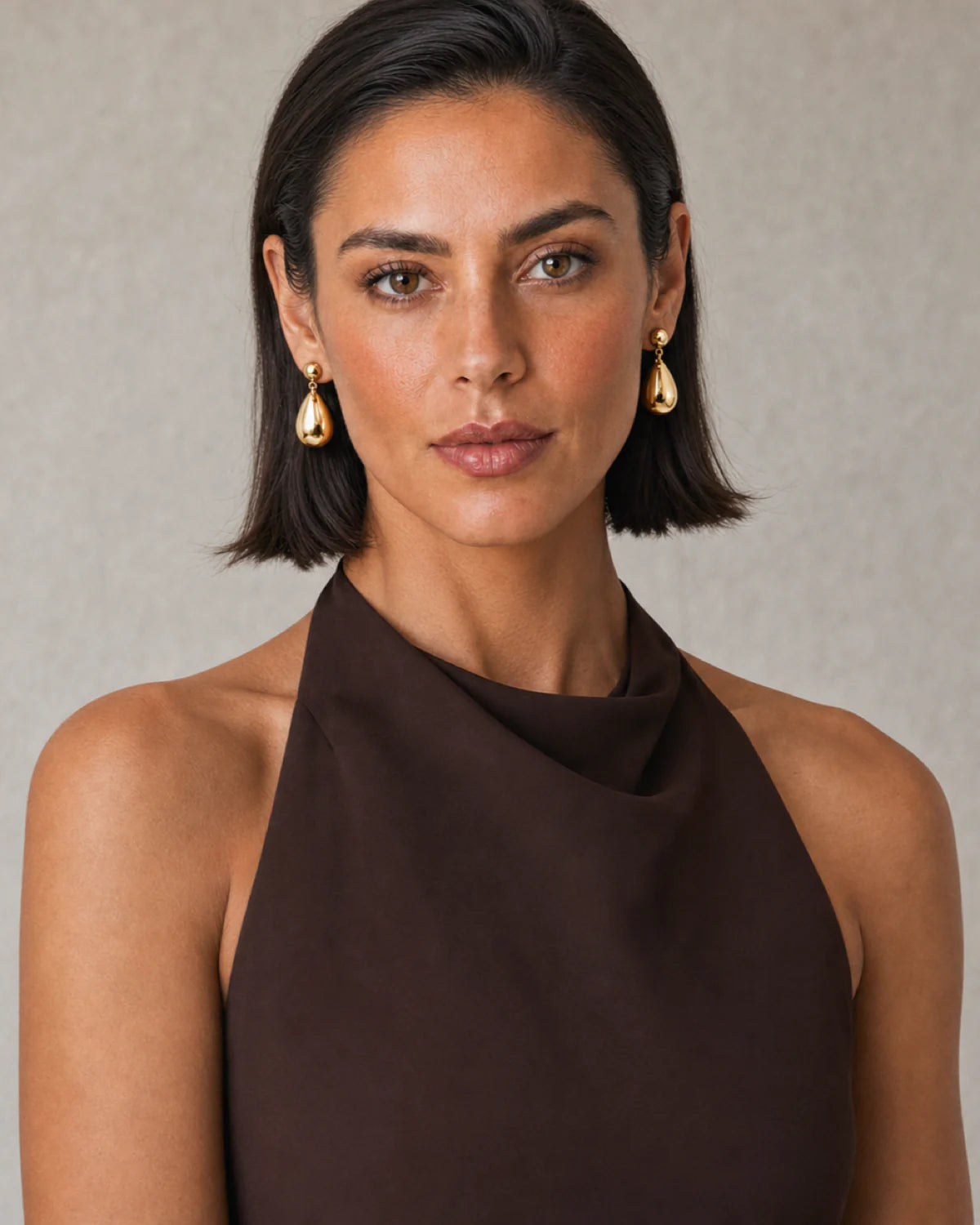 Bob-haired model wearing Luma gold teardrop earrings with a confident direct gaze