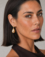 Clean ear and jaw close-up of a model wearing a Luma gold teardrop earring