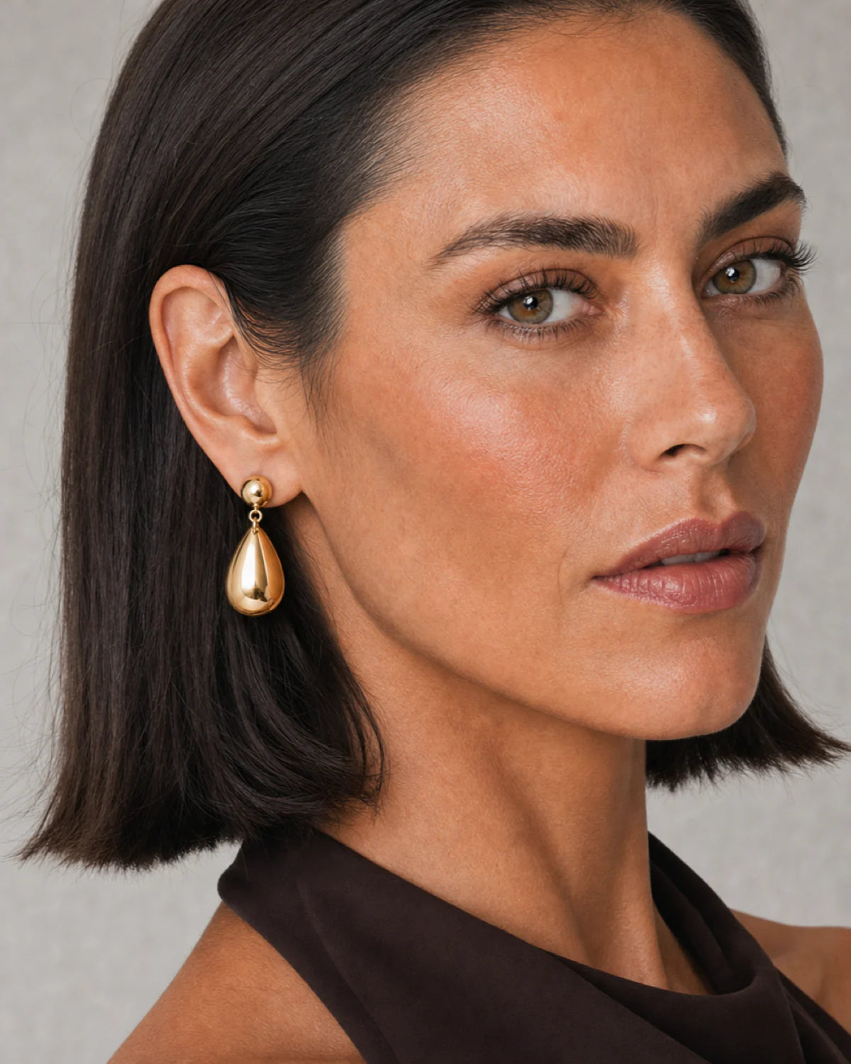 Clean ear and jaw close-up of a model wearing a Luma gold teardrop earring