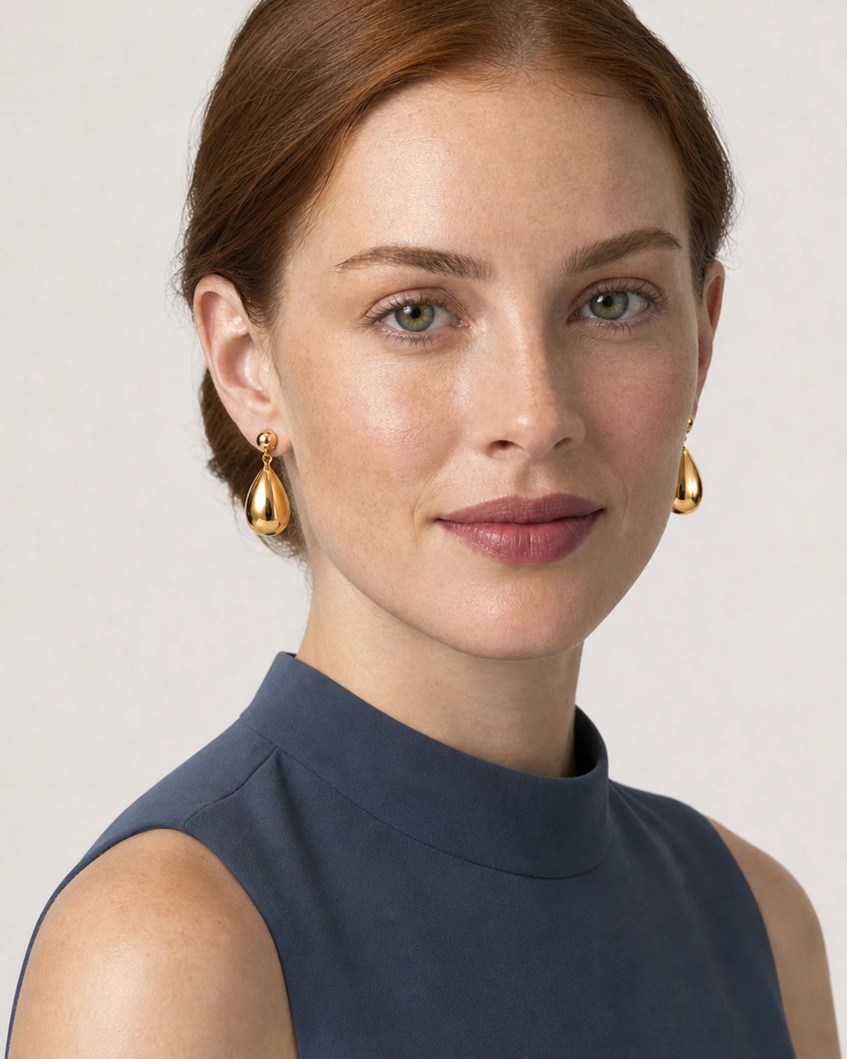 Three-quarter studio portrait wearing Luma gold teardrop earrings