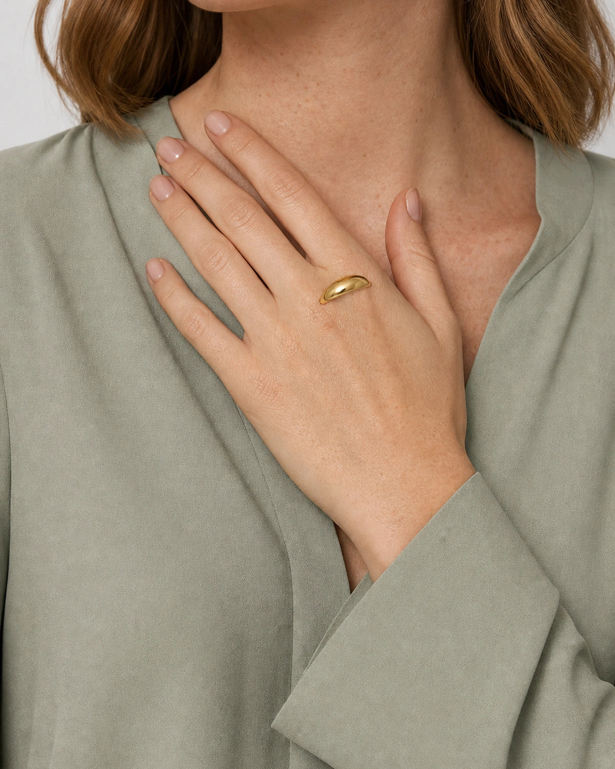 Lune gold dome ring worn with the hand raised diagonally toward the collarbone