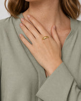 Lune gold dome ring worn with the hand raised diagonally toward the collarbone