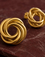 Macro of the Lyra interwoven gold knot studs on deep garnet stone