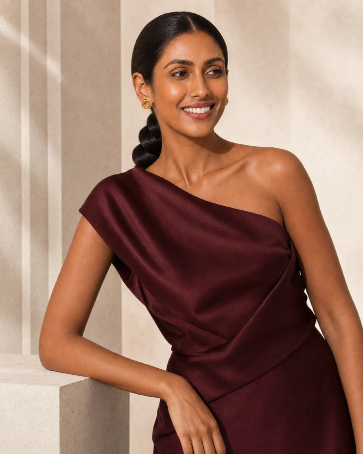 Smiling model beside limestone wearing Lyra gold circle knot earrings
