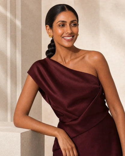 Smiling model beside limestone wearing Lyra gold circle knot earrings