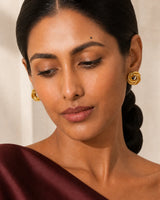 Clean wearing close-up of Lyra knot studs with the model looking down