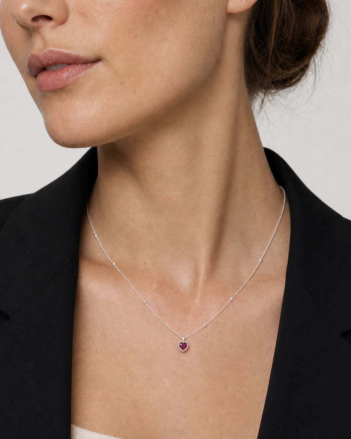 Close neckline portrait showing the petite Maëlle crimson heart pendant
