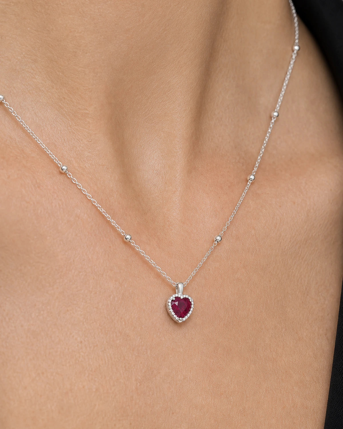 Extreme on-body macro of the Maëlle faceted crimson heart pendant