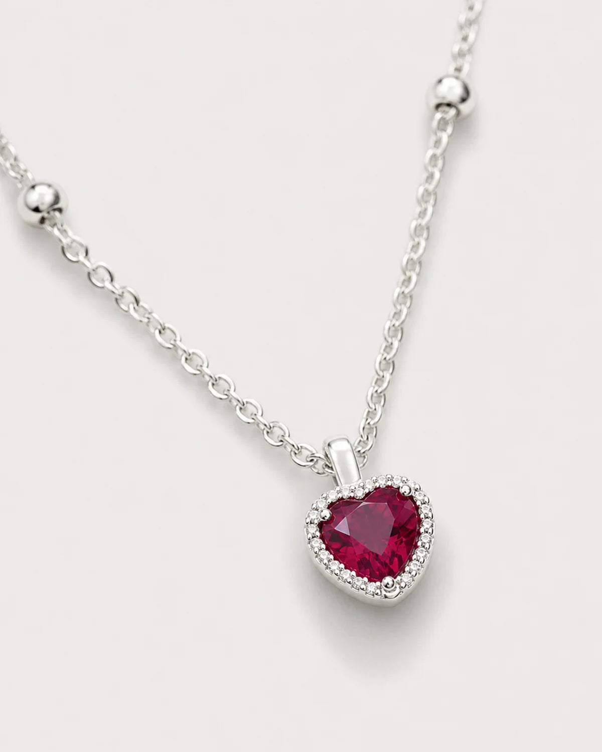 Macro of the faceted crimson heart, clear halo and silver Maëlle station chain