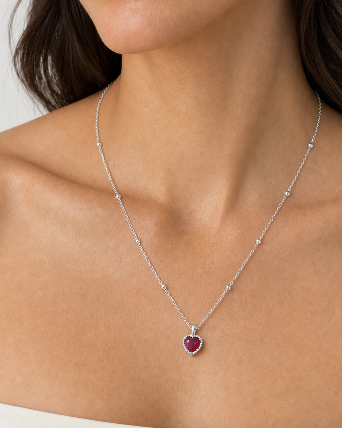 Eye-free frontal portrait of Elise wearing the silver Maëlle crimson heart necklace