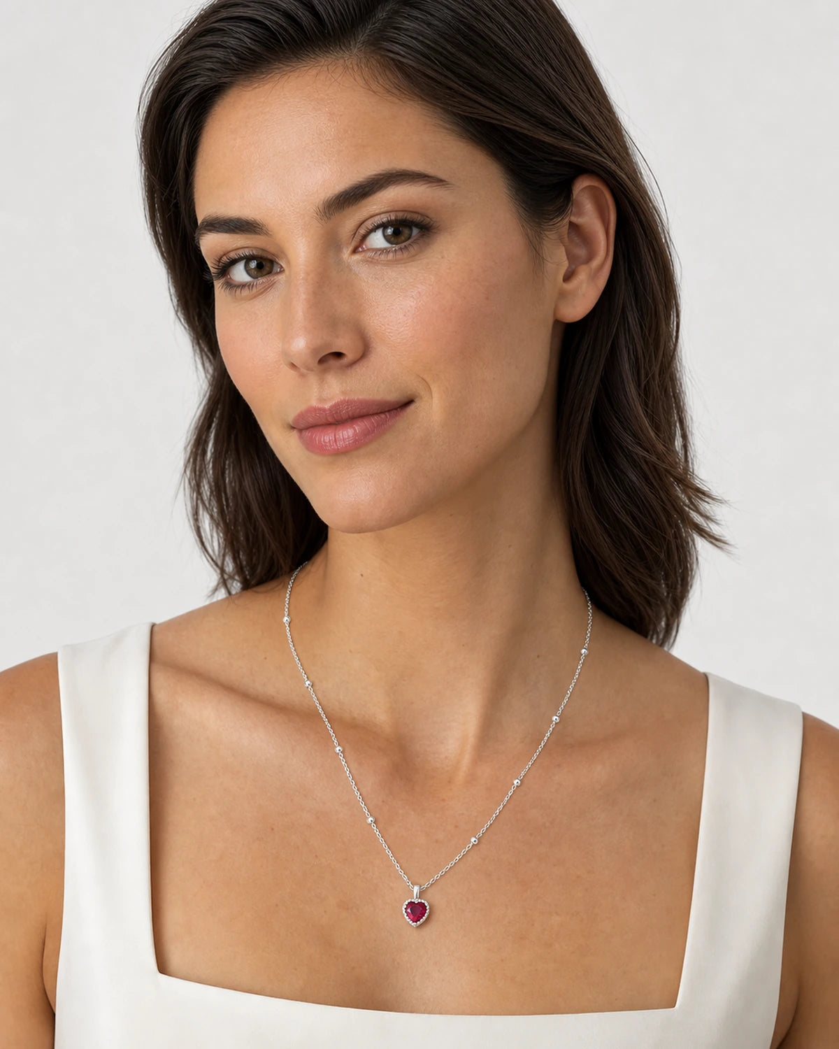 Model wearing the Maelle silver crimson heart station necklace on dove grey