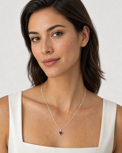 Model wearing the Maelle silver crimson heart station necklace on dove grey