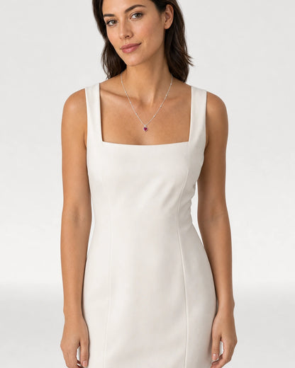 Waist-up ivory dress portrait featuring the Maelle crimson heart necklace