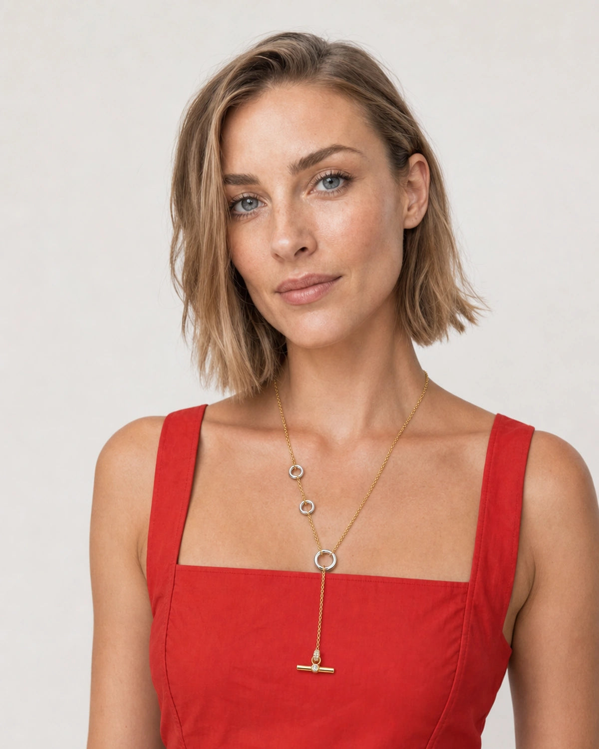Model in a tomato-red Sicilian sundress wearing the Marais mixed-metal lariat