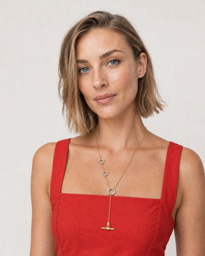 Model in a tomato-red Sicilian sundress wearing the Marais mixed-metal lariat