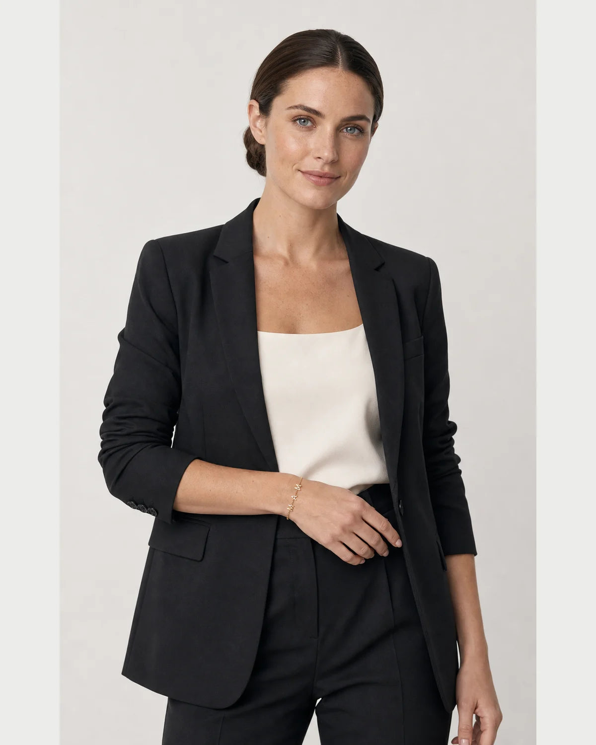 Australian model aged 26 to 28 wearing the Maren Mama letter bracelet in a pale dove-grey studio