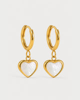 Pair of Maris gold mother-of-pearl heart huggies on a pale neutral-grey studio background