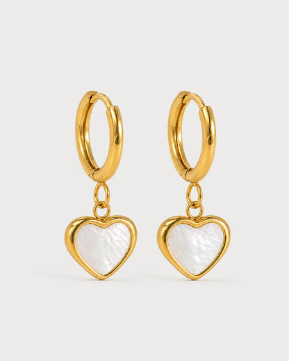 Pair of Maris gold mother-of-pearl heart huggies on a pale neutral-grey studio background