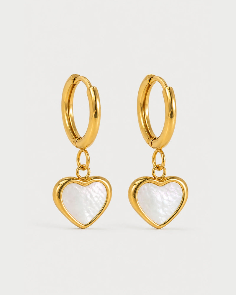 Pair of Maris gold mother-of-pearl heart huggies on a pale neutral-grey studio background