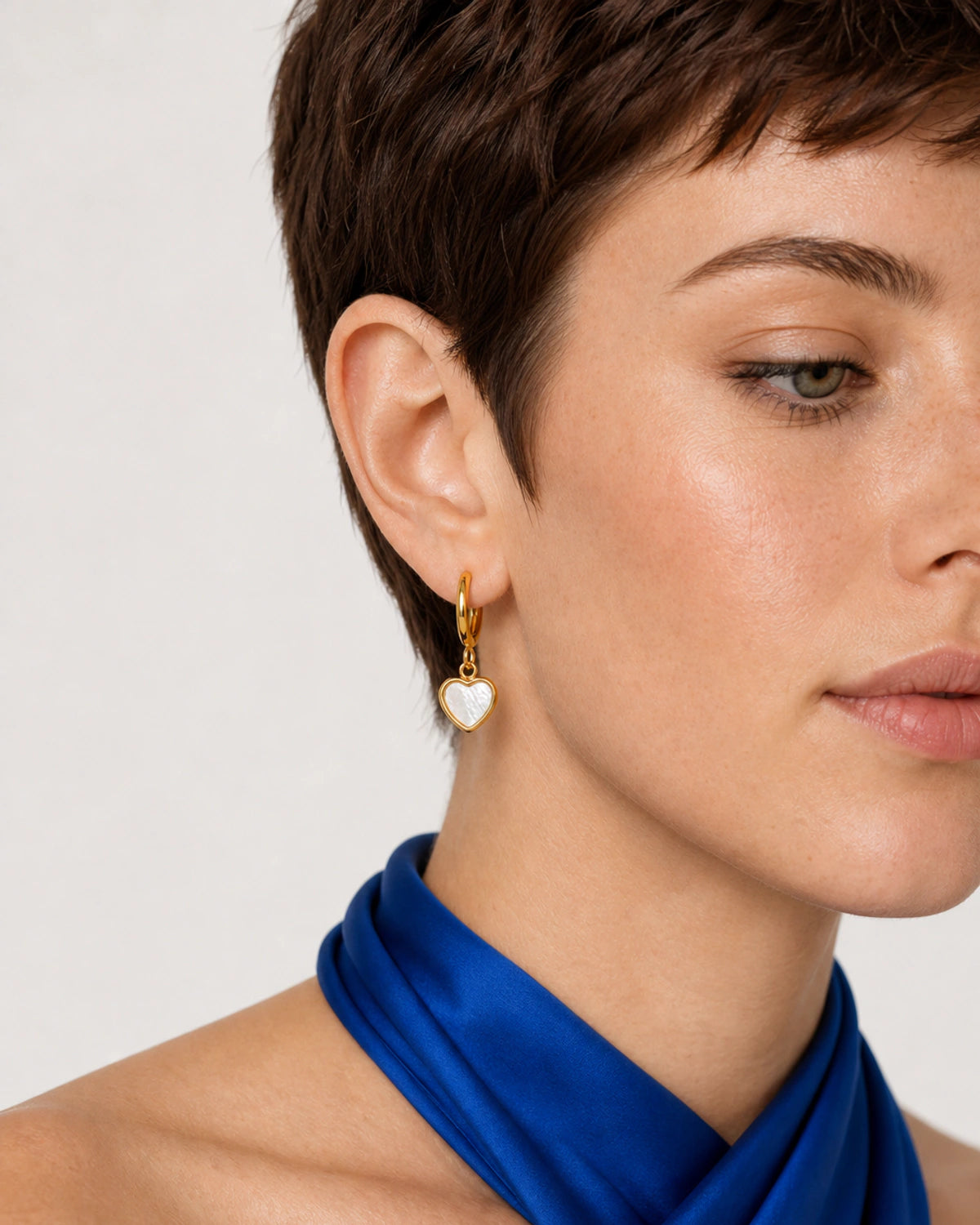 Close wearing view of the Maris gold huggie and mother-of-pearl heart