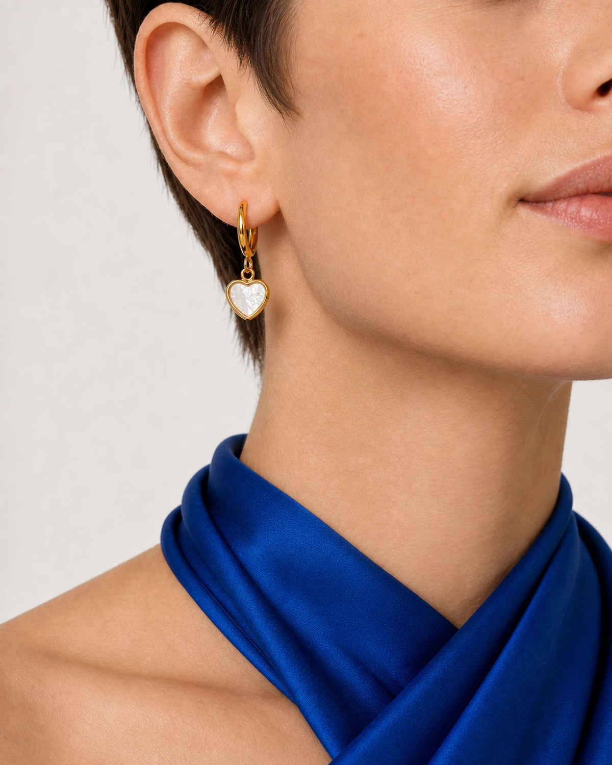 Eye-free front-three-quarter ear and mouth crop wearing a Maris heart huggie