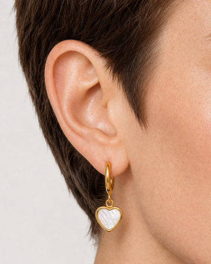Lateral extreme worn macro of the Maris gold huggie and luminous mother-of-pearl heart