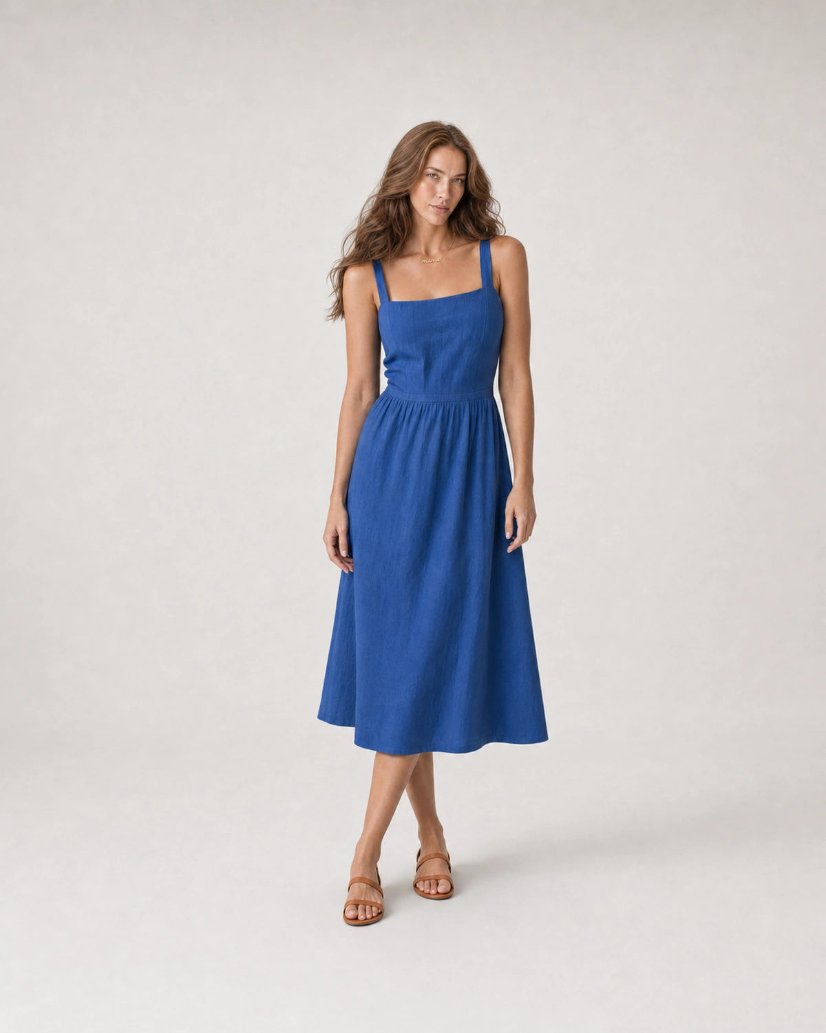 Wide studio portrait in a cobalt linen midi dress featuring the Mila necklace