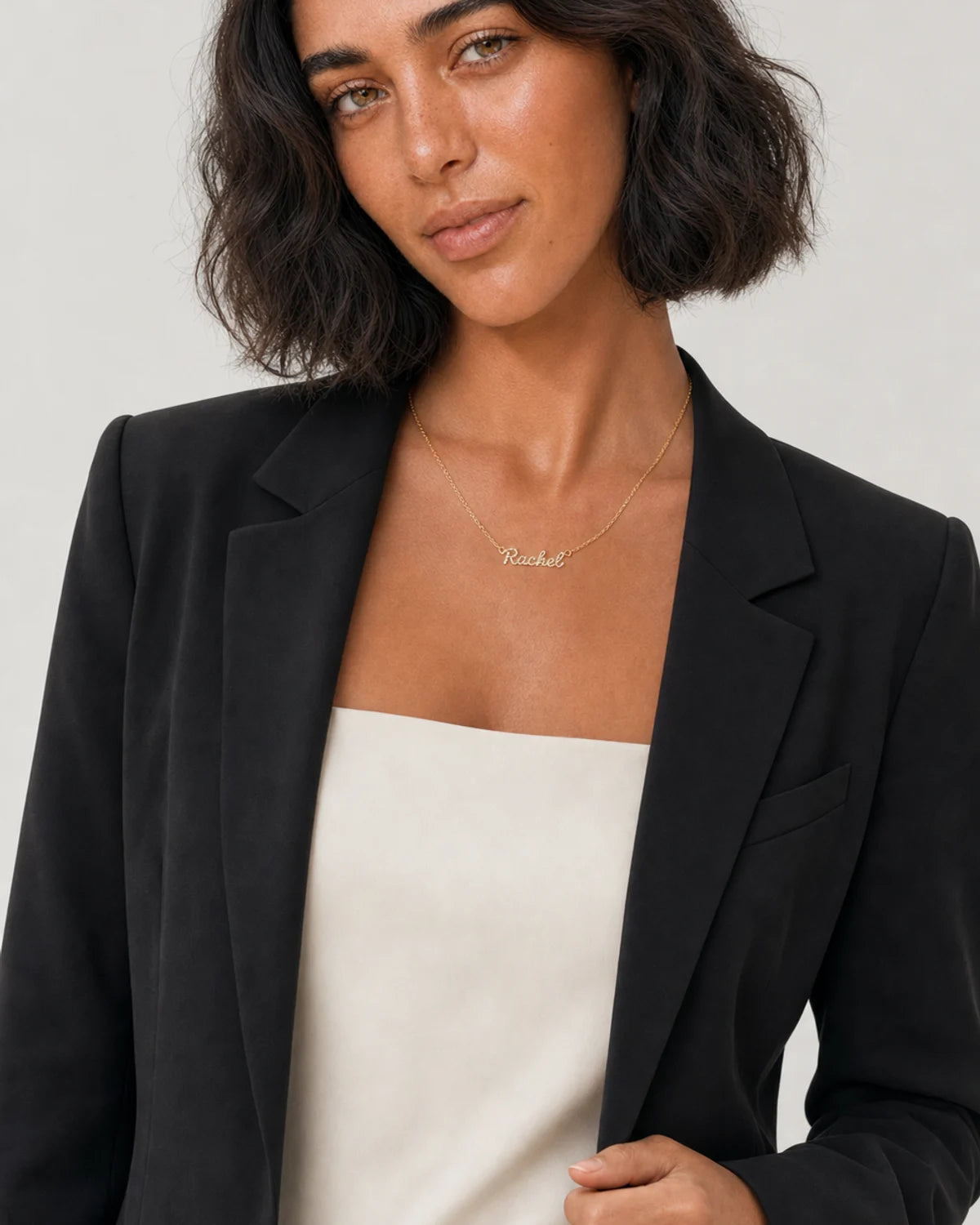 Model in black tailoring wearing the Mira Rachel name necklace