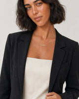 Model in black tailoring wearing the Mira Rachel name necklace