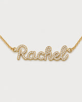 Macro view of the gold Mira connected cursive Rachel nameplate and clear pavé