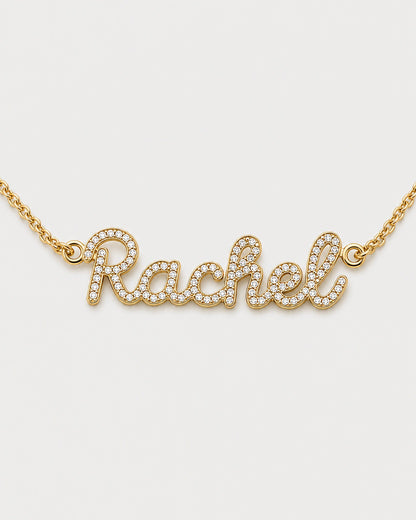 Macro view of the gold Mira connected cursive Rachel nameplate and clear pavé