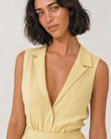 Model in a butter-yellow linen summer dress wearing the Mira Rachel necklace