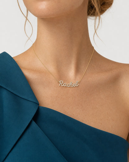 Mouth-down studio portrait wearing the gold Mira Rachel necklace with a petrol-teal silk top