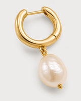 Macro view of Mirelle sculpted gold huggie and organic pearl