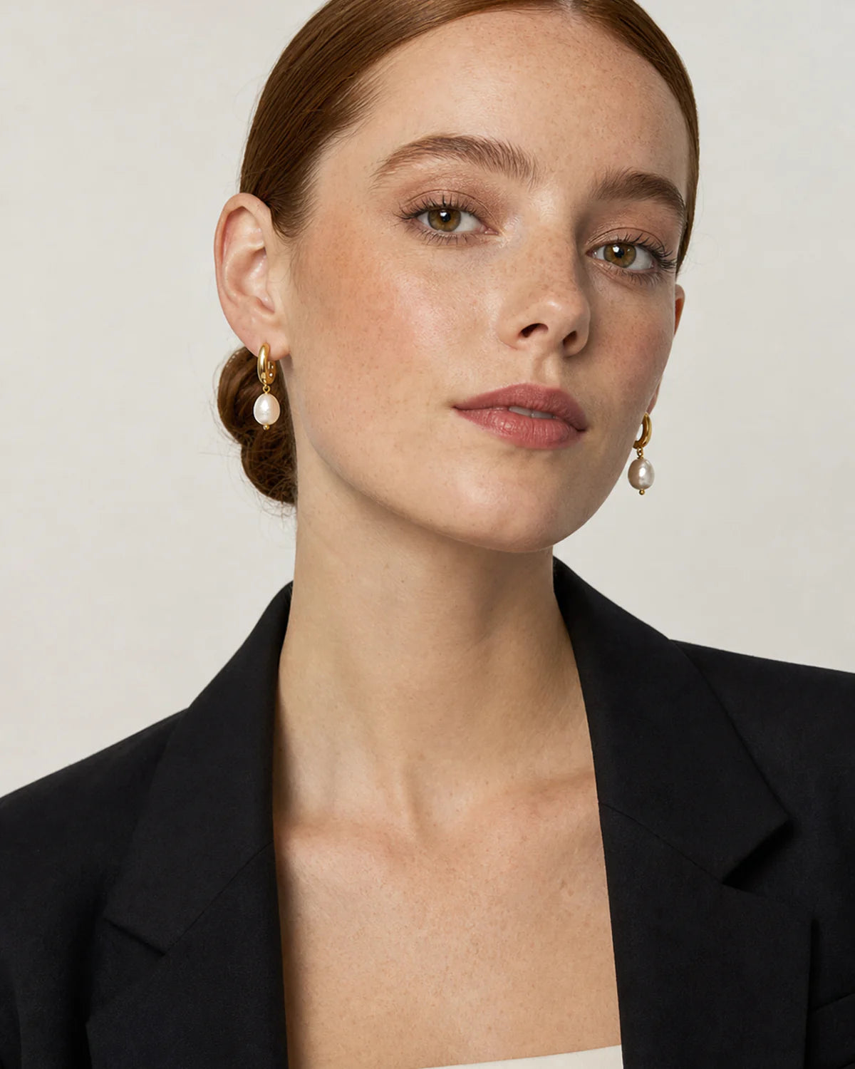 British model in black tailoring wearing Mirelle pearl earrings