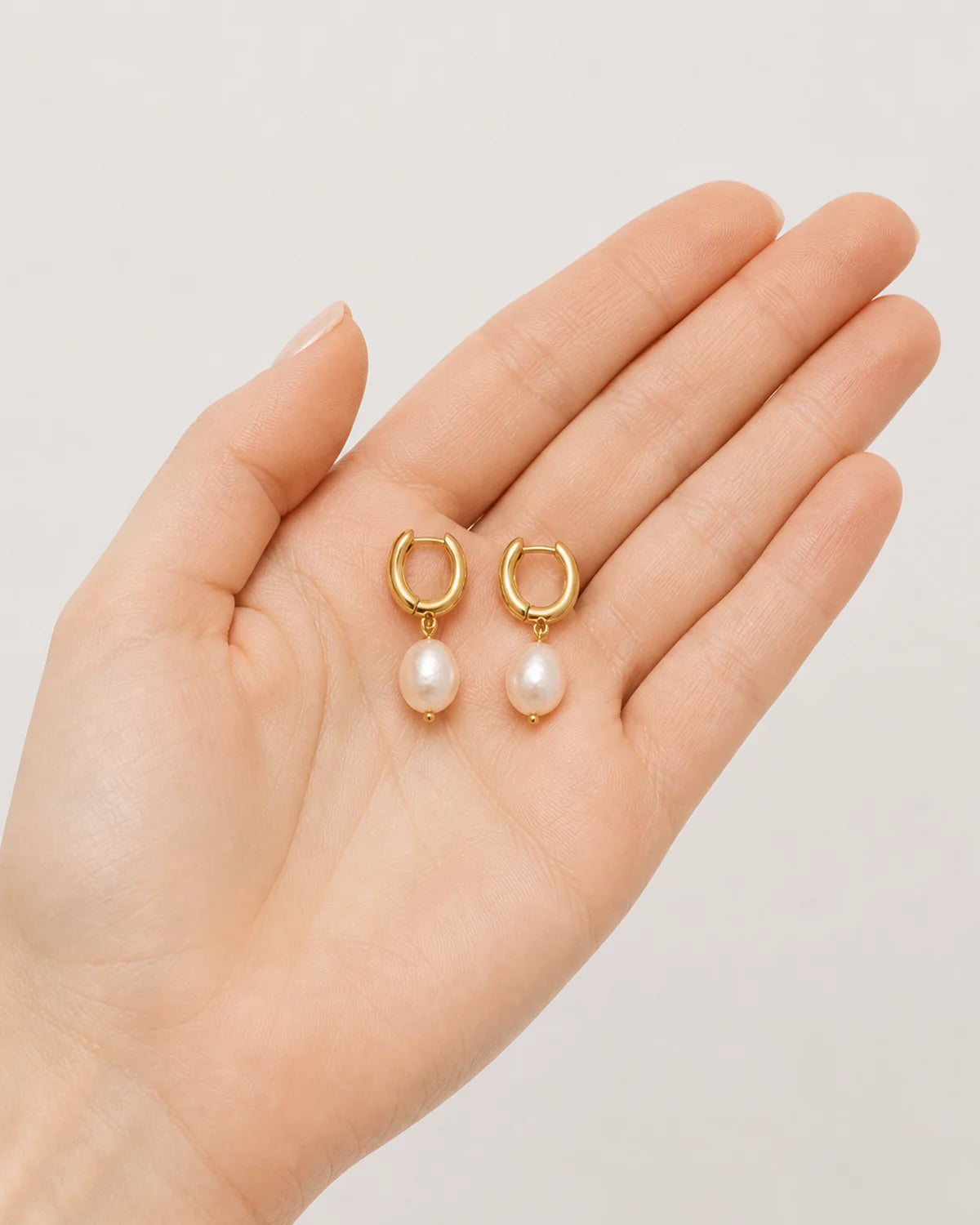 Hand-held scale view of the Mirelle pearl earring pair