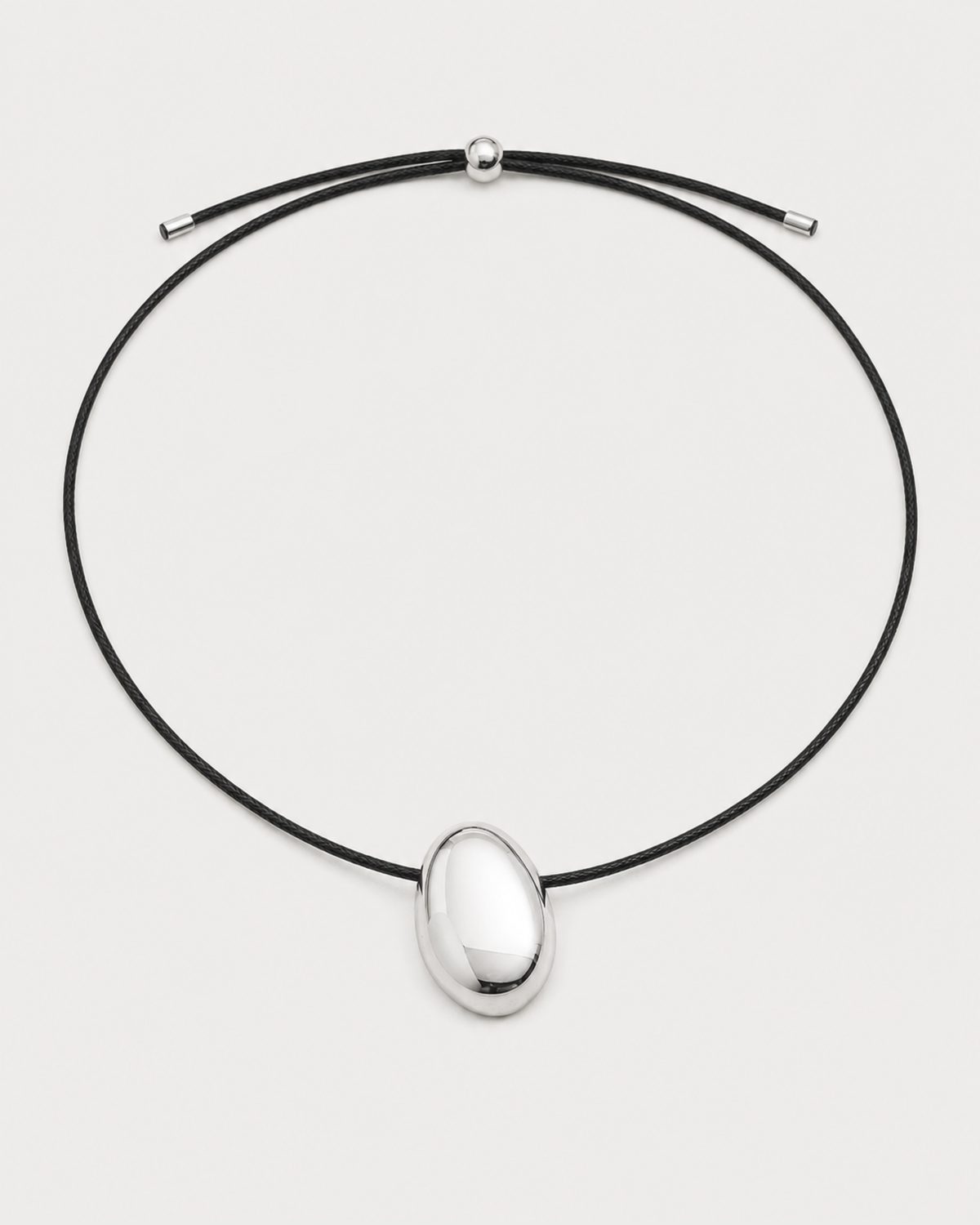 Naiya silver pebble cord necklace on a seamless pale dove-grey studio background