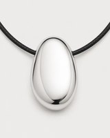 Macro front detail of the Naiya mirror-polished silver pebble and side-threaded black cord
