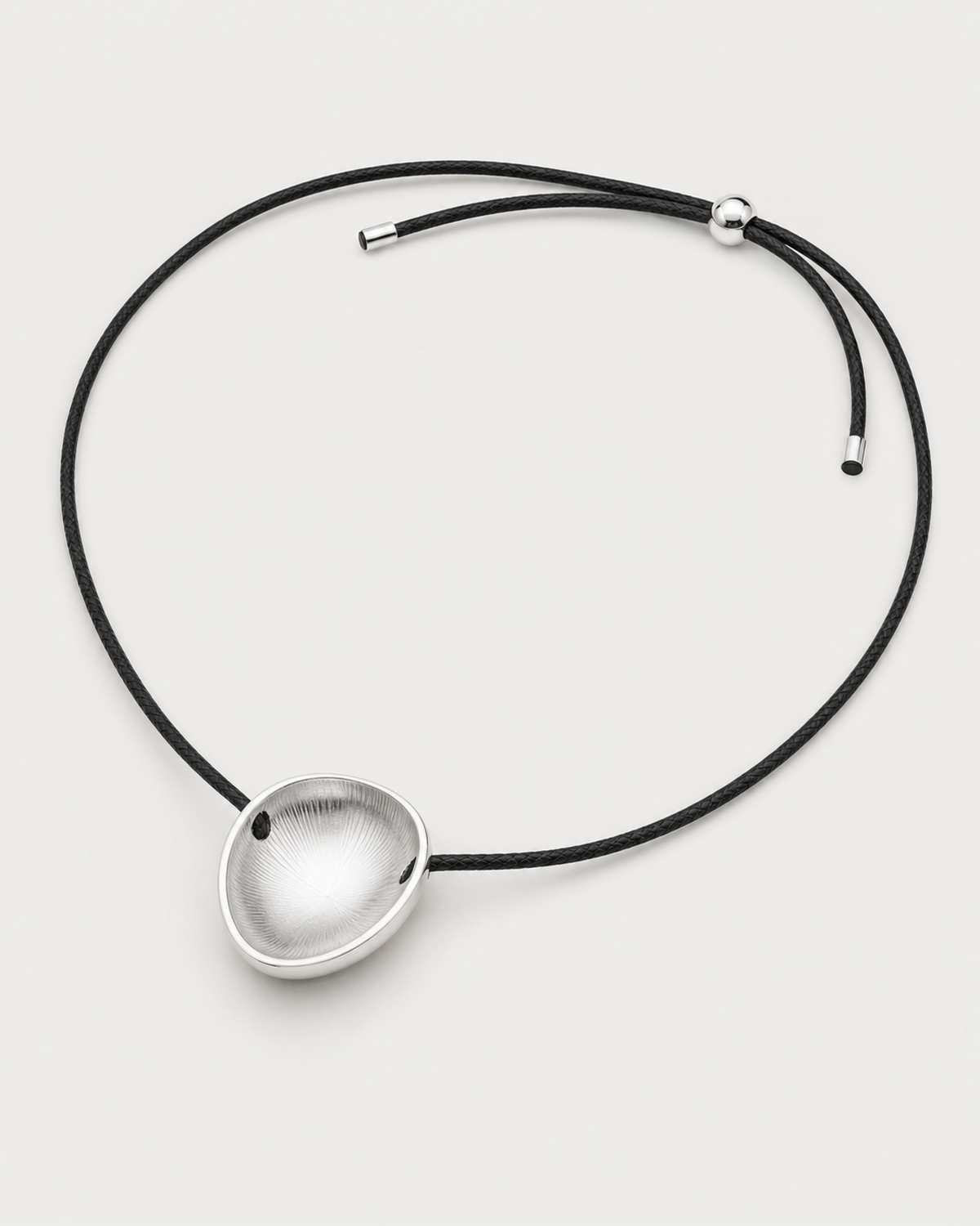 Reverse view of the Naiya concave silver pebble, braided cord, slider and end caps