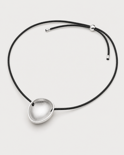 Reverse view of the Naiya concave silver pebble, braided cord, slider and end caps