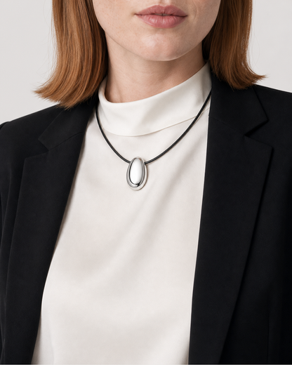Close wearing view of the Naiya mirror-polished silver pebble and black braided cord