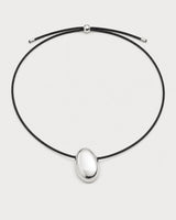 Naiya silver pebble cord necklace on a pale neutral-grey studio background
